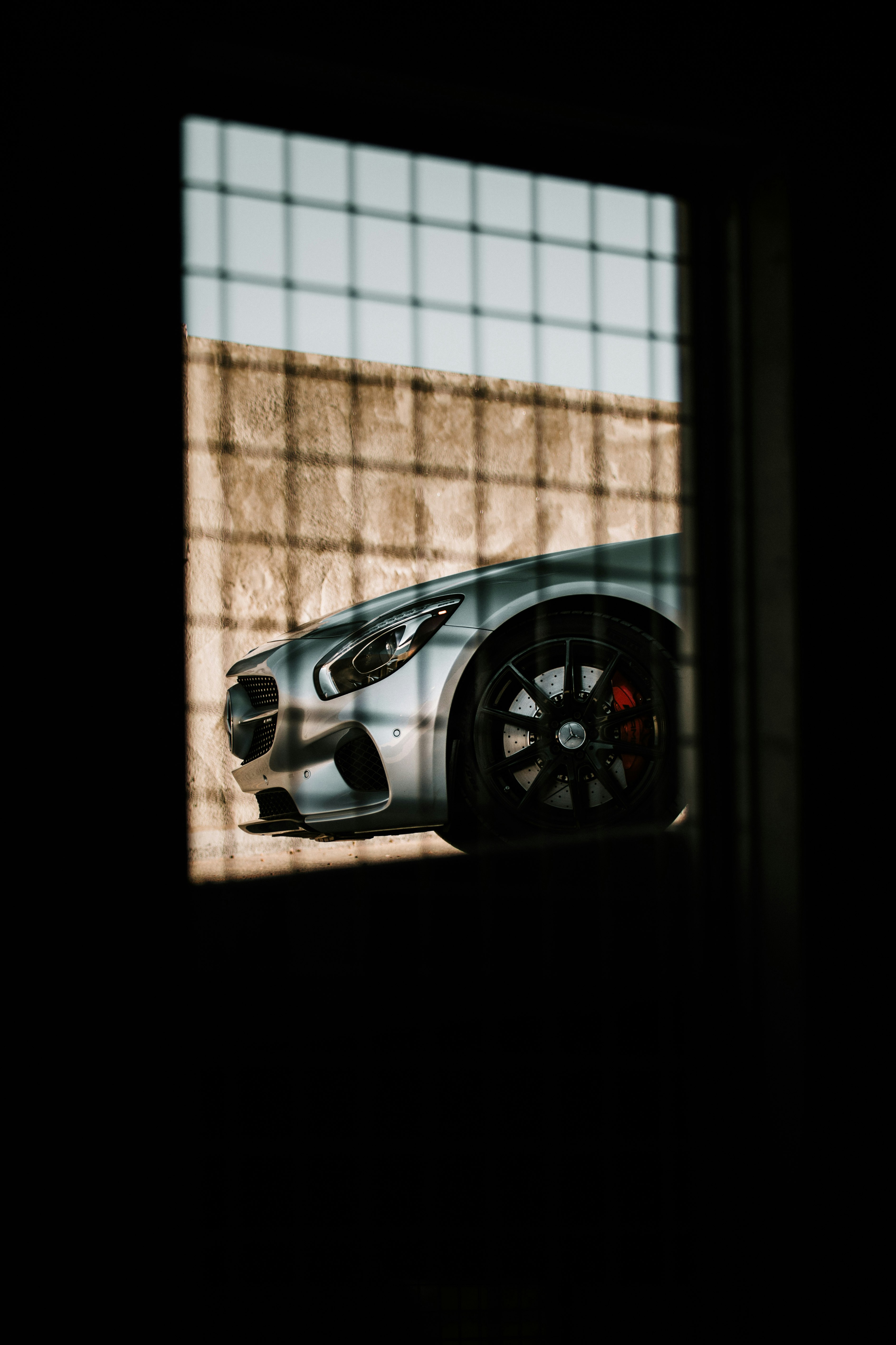 silver coupe parked beside brown brick wall